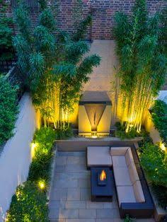Enclosed planted courtyard with evening lighting and a seating area.